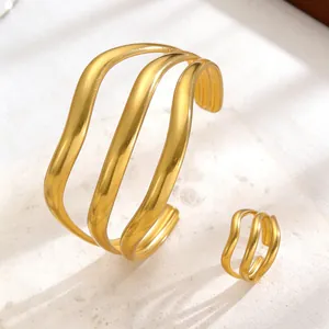 Detail view of wavy geometric gold metal bracelet and matching open ring set.