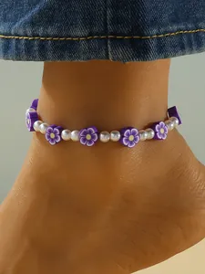 Vista macro detallada de una tobillera de flores de arcilla polimérica morada y perlas finas