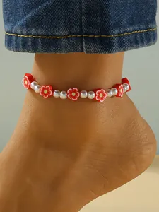 Vista detallada de una elegante tobillera con flores de arcilla roja y perlas blancas para mujer