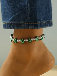 Primer plano de una elegante tobillera con cuentas de aguacate verdes y perlas blancas.