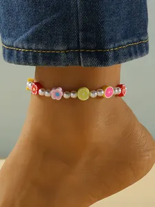 Detalle de una tobillera bohemia con perlas de imitación y dijes de arcilla colorida