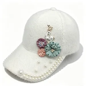Vue détaillée des fleurs faites à la main et des perles sur un chapeau d'hiver blanc
