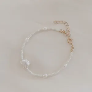 Detailed shot of irregular freshwater pearls and white seed beads on a gold-plated chain