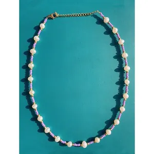 Macro detail of Bohemian dopamine style necklace with purple seed beads and freshwater pearls