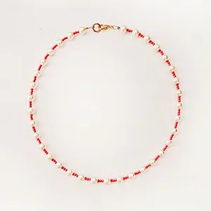 Detailed view of a Bohemian red and white beaded choker with pearls and a gold clasp.