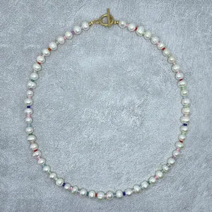 Detailed view of irregular freshwater pearls and rainbow seed bead necklace with gold clasp