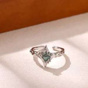 Macro detail of a silver geometric ring with green center stone and sparkling zircons