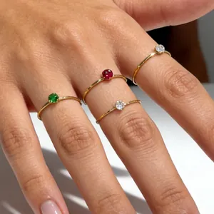 Detailed view of minimalist 14K gold thin rings with red, green and clear gemstones