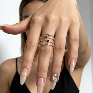 Close-up of four thin 14K gold rings with colorful gemstones on finger