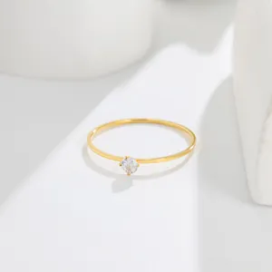 Close-up detail of a minimalist 14K gold ultra-thin ring with a small round-cut gemstone
