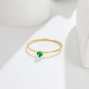 Close-up of a minimalist 14K gold thin ring featuring a brilliant round green gemstone.