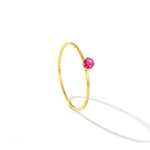 Macro view of a delicate 14K gold minimalist thin ring featuring a vibrant pink gemstone