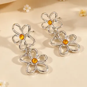 Detailaufnahme exquisiter silberner hohler Blumenohrringe mit orangefarbenen Kunstharzperlen