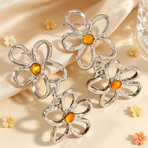 Detaillierte Nahaufnahme eleganter silberner hohler Blumenohrringe mit Bernsteinharz