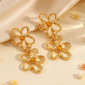 Elegante goldene durchbrochene Blumenohrringe mit bernsteinfarbenem Stein im Detail