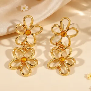 Nahaufnahme von goldfarbenen hohlen Blumenohrringen mit bernsteinfarbenen Steinen