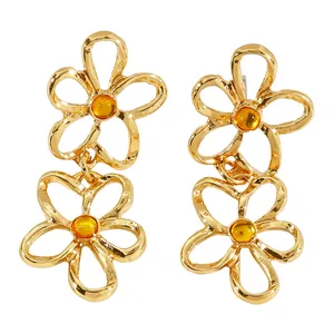 Detailansicht goldener hohler Blumenohrringe mit bernsteinfarbener Perle für Damen.