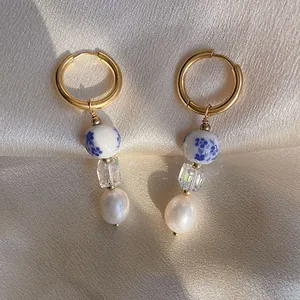 Vista dettagliata di eleganti orecchini a cerchio in ceramica blu e bianca con perle