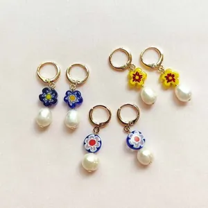 Dettaglio di orecchini a cerchio dorati con fiori in vetro colorato e perle d'acqua dolce.