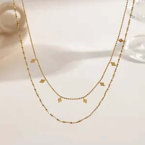 Macro detail of minimalist 18K gold plated titanium steel double layer necklace with rhombus charms