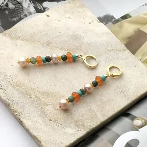 Dettaglio di orecchini pendenti fatti a mano con perle d'acqua dolce e pietre colorate
