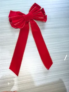Détail d'un grand nœud de Noël en velours rouge avec des bordures dorées cousues