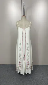Vue détaillée de la broderie florale rouge et du design superposé sur une robe maxi blanche