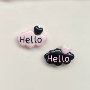 Gros plan de charms nuages en résine rose et noir avec texte Hello et cœurs.
