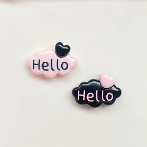 Gros plan de breloques nuage en résine rose et noir avec cœur et lettrage Hello