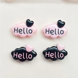 Gros plan sur des accessoires en résine rose et noir en forme de nuage avec motif Hello