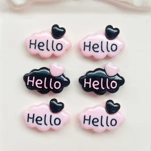 Gros plan de breloques en résine nuage rose et noir avec cœurs et imprimé Hello
