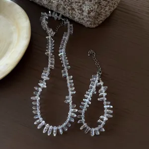 Detailed view of clear irregular crystal stone necklace and bracelet set on wooden surface