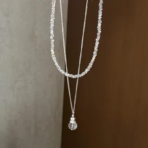 Detailed view of irregular crystal stone beads and silver chain with transparent drop pendant