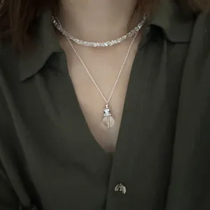 Close-up of layered irregular crystal gravel choker and transparent orb pendant necklace