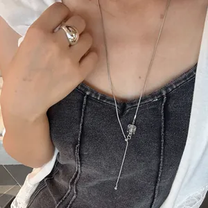 Detail shot of woman wearing elegant long silver necklace with irregular crystal pendant
