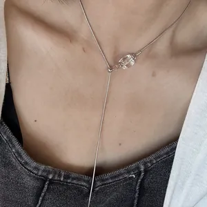 Detail view of a minimalist silver Y-necklace with a faceted clear crystal pendant.