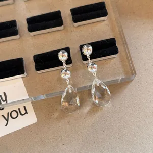 Detailed view of elegant silver drop earrings with faceted clear teardrop crystals.