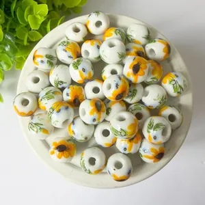 Close-up detail of 10mm white ceramic loose beads with vibrant yellow sunflower patterns
