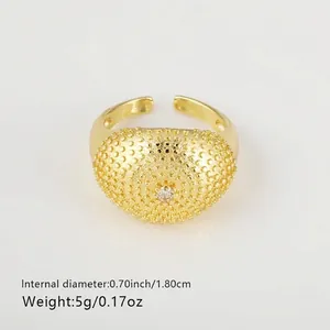 Detail of a punk style gold-plated open ring featuring a textured dome with a small zircon.
