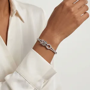 Elegant silver-tone panther bangle encrusted with zircons, styled on model's wrist.