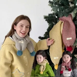 Bambino che indossa uno scaldacollo in maglia a righe spesse con simpatici pon pon