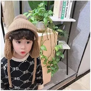 Bambino che indossa un berretto di maglia marrone alla moda con paraorecchie e pompon