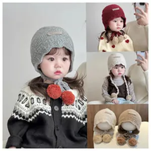 Vista dettagliata del cappello in maglia per neonati con grandi pompon decorativi