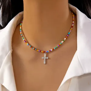 Detail view of a vibrant colorful beaded necklace with sparkling crystal cross pendant