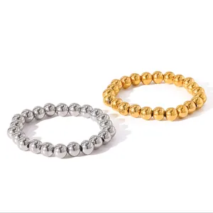 Close-up of gold and silver stainless steel bead elastic bracelets on white background