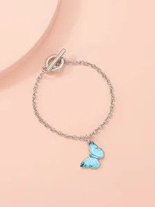 Detail shot of a silver chain bracelet with a blue butterfly pendant and OT buckle