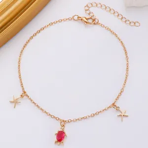 Detailansicht der goldfarbenen Bohemian-Fußkette mit Schildkröten- und Seesternanhängern