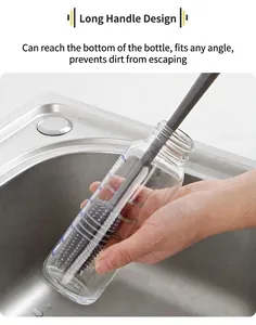Long handle silicone brush cleaning the bottom of a glass bottle in a kitchen sink