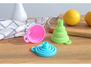 Trois entonnoirs pliables en silicone colorés sur une table en bois avec des citrons frais.