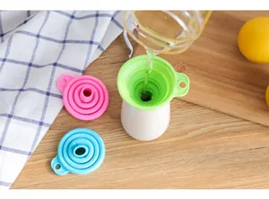 Entonnoir pliable en silicone vert versant de l'eau dans une bouteille dans une cuisine